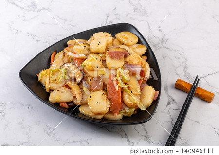 stir fried sliced rice cakes with mushrooms, vegetables and meat in spicy sauce. 140946111
