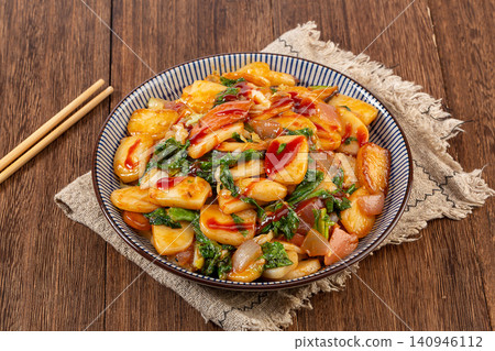 stir fried sliced rice cakes with mushrooms, vegetables and meat in spicy sauce. 140946112