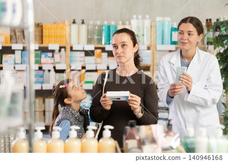 Middle-aged woman with daughter choosing ointment in drugstore Middle-aged woman with daughter choosing ointment in drugstore 140946168