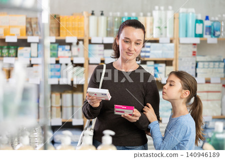 Woman with daughter choosing paracetamol in pharmacy Woman with daughter choosing paracetamol in pharmacy 140946189