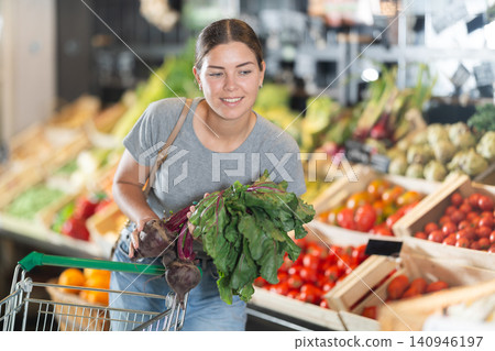 In vegetable department of bio supermarket, female customer took bunch of beets from window In vegetable department of bio supermarket, female customer took bunch of beets from window 140946197