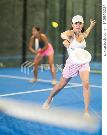 Woman playing padel on open court on summer day. Sport and active lifestyle concept Woman playing padel on open court on summer day. Sport and active lifestyle concept 140946224