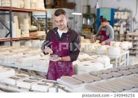 Craftsman showcasing slipcast ceramic piece in artisanal workshop 140946258