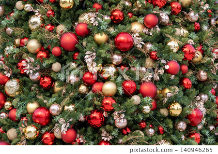 Detailed shot of Christmas tree branches covered with colorful baubles, ribbons and glowing lights forming a rich, cheerful backdrop. Detailed shot of Christmas tree branches covered with colorful baubles, ribbons and glowing lights forming a rich, cheerful backdrop. 140946265