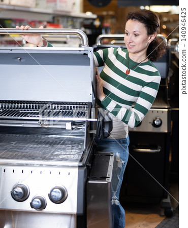 Woman looking at new bbq grill in showroom Woman looking at new bbq grill in showroom 140946425