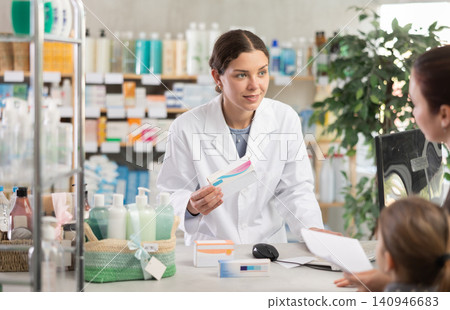 Pharmacist helping woman with girl choose medications at pharmacy Pharmacist helping woman with girl choose medications at pharmacy 140946683