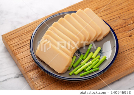 sliced Chinese Rice Tofu on Plate with Garlic Scapes Ready to Cook 140946958
