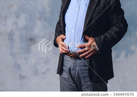 The torso of a man with his hand on his stomach The torso of a man with his hand on his stomach 140947070