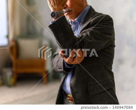 A man hugging his elbows indoors A man hugging his elbows indoors 140947084