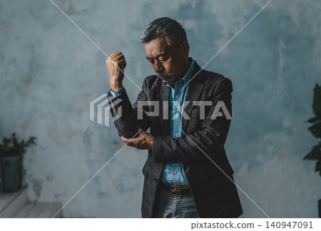 A man clutching his elbow in distress. A man clutching his elbow in distress. 140947091