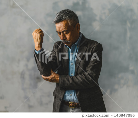 An elderly man supporting his elbow An elderly man supporting his elbow 140947096