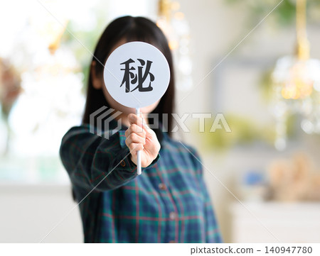 A woman with her face hidden, holding a secret card. A woman with her face hidden, holding a secret card. 140947780