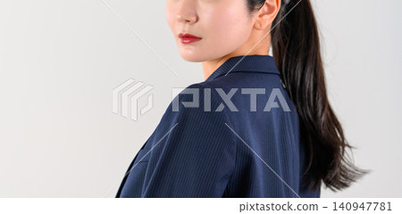 A woman in a suit turns around over her shoulder. A woman in a suit turns around over her shoulder. 140947781