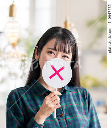 A young Japanese woman holding a tag with an "X" mark on it. A young Japanese woman holding a tag with an "X" mark on it. 140947783