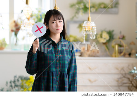 A woman in a dress holding a sign with an "X" on it. A woman in a dress holding a sign with an "X" on it. 140947794