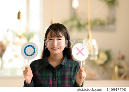 一位年輕女子舉著畫有圓圈和十字架的牌子。 一位年輕女子舉著畫有圓圈和十字架的牌子。 140947798