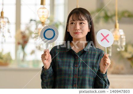 一位年輕女子手持圓圈和X形符號 140947803