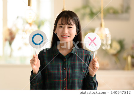 A woman smiling, holding cards with circles and crosses. 140947812