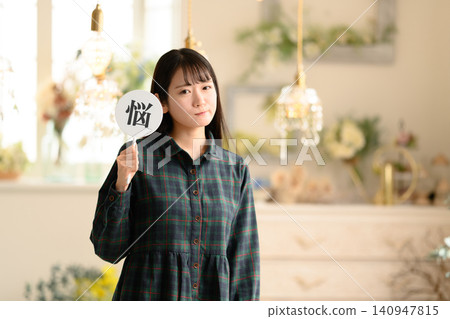 A woman holding a fan with the character for "worry" written on it. 140947815