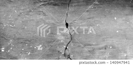 A high-contrast, black-and-white close-up photo showing the texture of a cracked concrete wall. 140947941