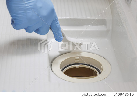 俯拍鏡頭顯示一隻戴著藍色手套的手正在用刷子攪起泡沫,清潔浴缸排水口周圍。 俯拍鏡頭顯示一隻戴著藍色手套的手正在用刷子攪起泡沫,清潔浴缸排水口周圍。 140948519