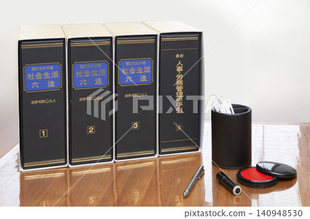 辦公桌上擺放著社會法和人力資源管理的書籍，以及郵票架和筆架。 140948530