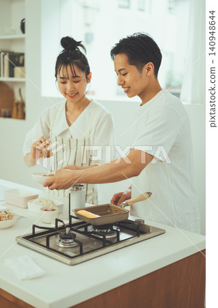 A couple making lunch side-by-side in a bright kitchen. A couple making lunch side-by-side in a bright kitchen. 140948644