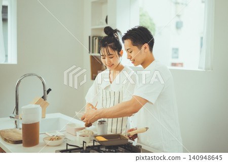 A couple making lunch side-by-side in a bright kitchen. 140948645