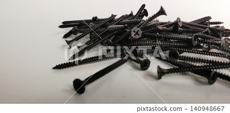 A pile of black drywall screws against a white background. A pile of black drywall screws against a white background. 140948667