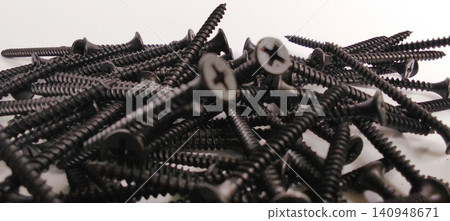 A pile of black drywall screws against a white background. A pile of black drywall screws against a white background. 140948671