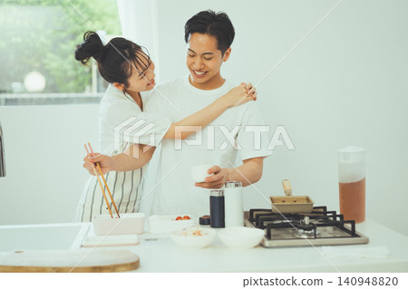A smiling couple, with the man leaning against her while she cooks in the kitchen. A smiling couple, with the man leaning against her while she cooks in the kitchen. 140948820