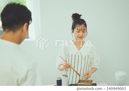 一名男子看著一名女子在廚房裡煎雞蛋。 一名男子看著一名女子在廚房裡煎雞蛋。 140949003