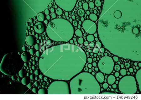 Closeup view of green illuminated bubbles and foam cells suspended in liquid, creating organic microscopic texture with dark outlines and scientific abstract Closeup view of green illuminated bubbles and foam cells suspended in liquid, creating organic microscopic texture with dark outlines and scientific abstract 140949240