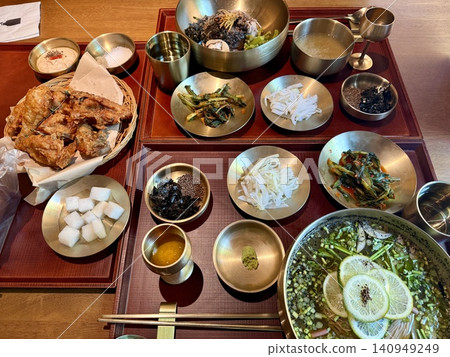 A luxurious lunch table featuring cold noodles, fried chicken, and small side dishes of namul. 140949249