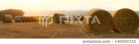 A landscape of straw bales on the hills of Biei, bathed in the light of the setting sun in the summer twilight. A landscape of straw bales on the hills of Biei, bathed in the light of the setting sun in the summer twilight. 140950728