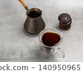 Cup of coffee, a cezve and chocolate-dipped cookies on the kitchen table. 140950965
