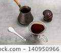 Cup of coffee, a cezve and chocolate-dipped cookies on the kitchen table. 140950966