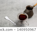 Cup of coffee, a spoon and a cezve on the kitchen table. 140950967