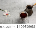 Cup of coffee, a cezve and an orchid flower on the kitchen table. 140950968