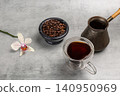 Stone bowl with roasted coffee beans, a cup of coffee and a cezve. 140950969