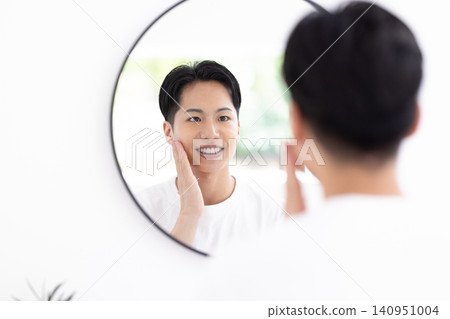 美妝圖片:一位男士正在對著鏡子進行護膚。 美妝圖片:一位男士正在對著鏡子進行護膚。 140951004