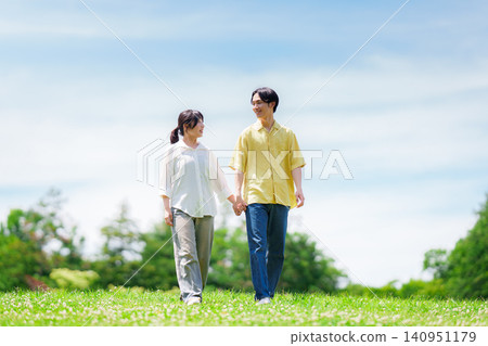 A couple walking in a park under a blue sky A couple walking in a park under a blue sky 140951179
