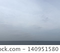 A calm sea stretches out under a cloudy sky, with a small boat floating on the horizon. 140951580