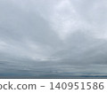 A calm sea and a cloudy sky stretch across the horizon. 140951586