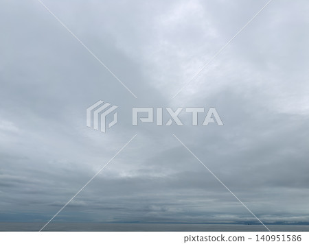 A calm sea and a cloudy sky stretch across the horizon. A calm sea and a cloudy sky stretch across the horizon. 140951586