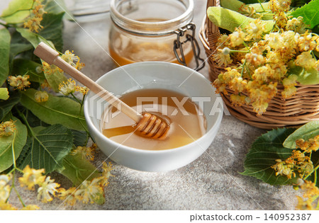 Linden honey in bowl with medicinal flowers Linden honey in bowl with medicinal flowers 140952387