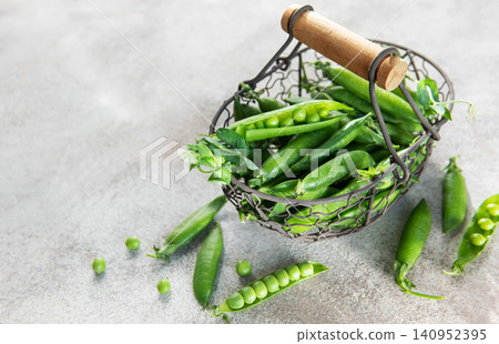 Fresh green peas pods in metal basket harvesting concept Fresh green peas pods in metal basket harvesting concept 140952395