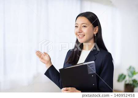 A young Japanese businesswoman guides a client while carrying files. A young Japanese businesswoman guides a client while carrying files. 140952458