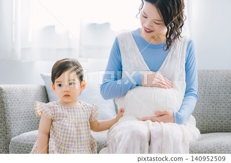 一個小女孩和她懷孕的母親在客廳玩耍。 一個小女孩和她懷孕的母親在客廳玩耍。 140952509