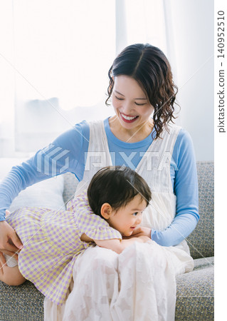 一位懷孕的母親抱著她1歲的女兒在客廳。 一位懷孕的母親抱著她1歲的女兒在客廳。 140952510